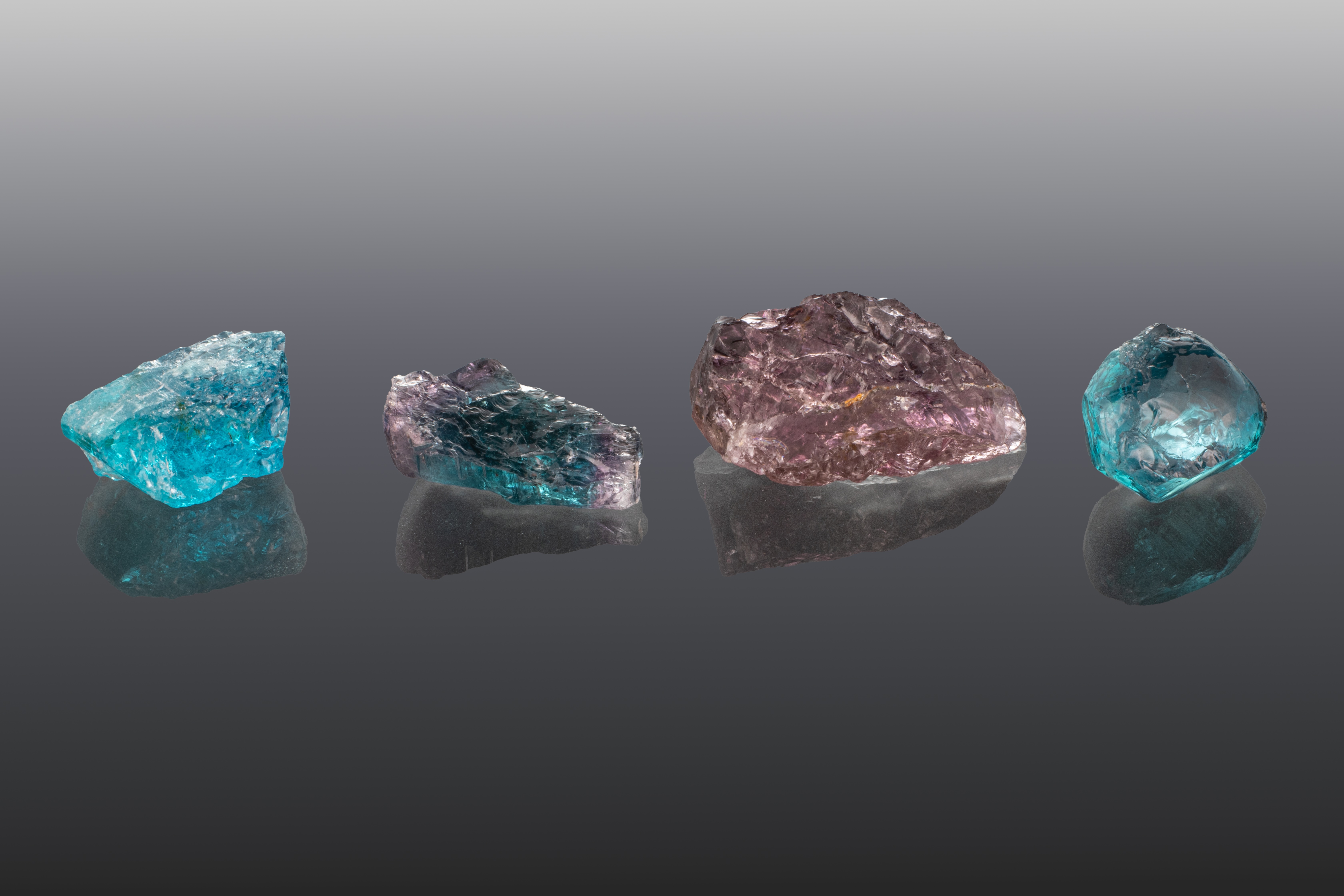 Rough Ethiopian paraíba tourmalines showing blue, green, violet, and purple colors, ranging from 4.20 to 10.95 carats.